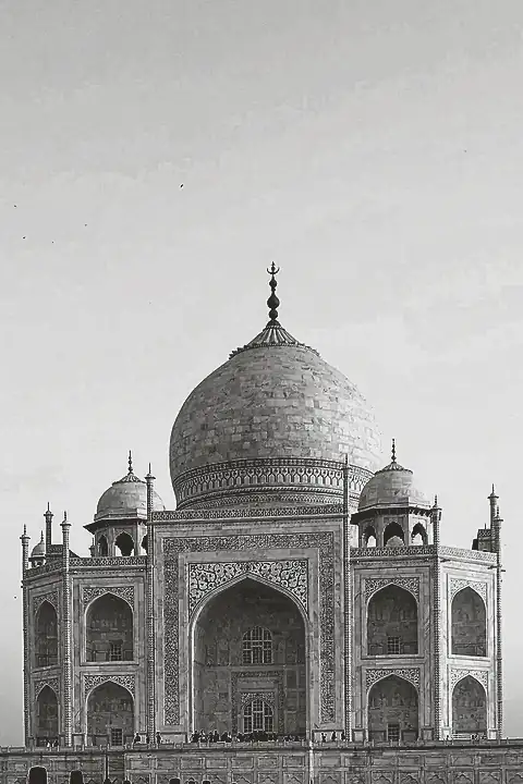 A white marble mausoleum with a large central dome, in early-morning light.